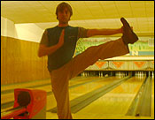 Noel doing a yoga pose after bowling a strike.